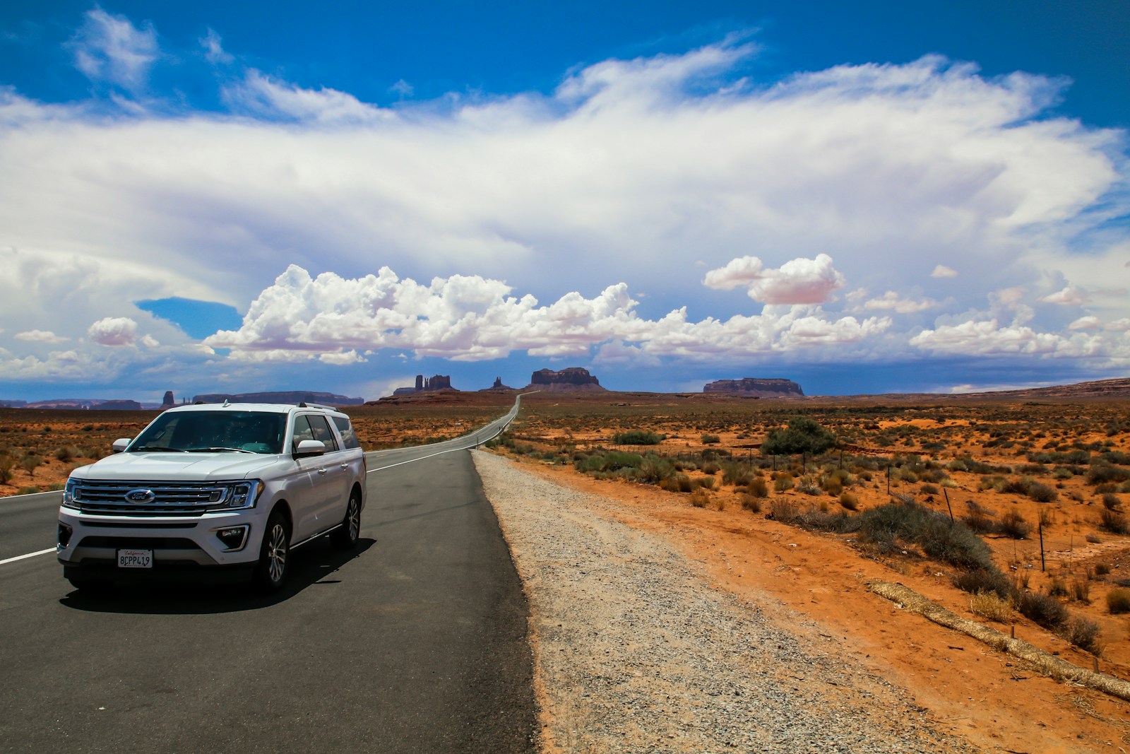 a white suv driving down a desert road